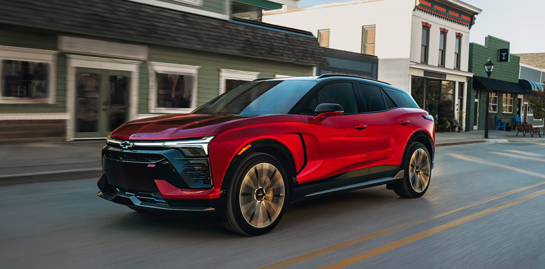 A red 2026 Chevrolet Blazer EV driving down the road.